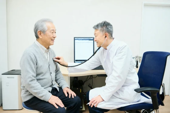 聴診器で診察を受ける患者さまと院長